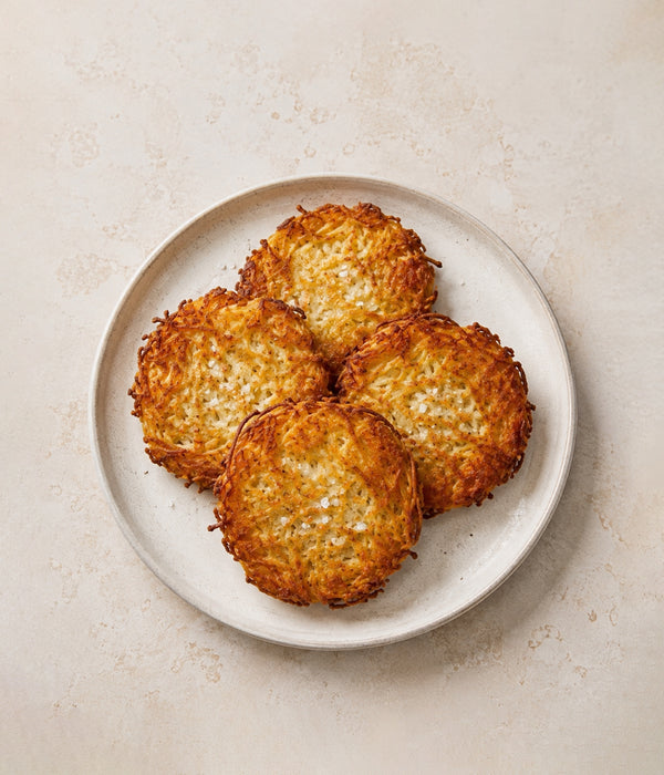 Four crisp golden hash browns on a pale plate